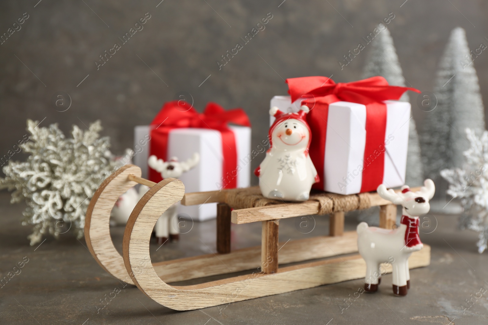 Photo of Beautiful Christmas composition with miniature sleigh on grey table
