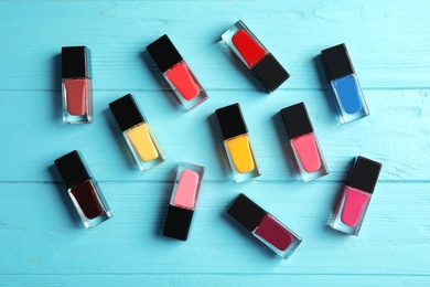 Bottles of nail polish on color background, top view