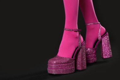 Photo of Woman wearing pink tights and high heeled shoes with platform and square toes on black background, closeup. Space for text