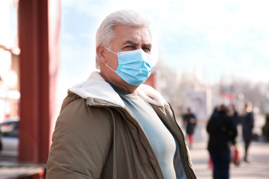 Photo of Senior man with medical mask on city street. Virus protection