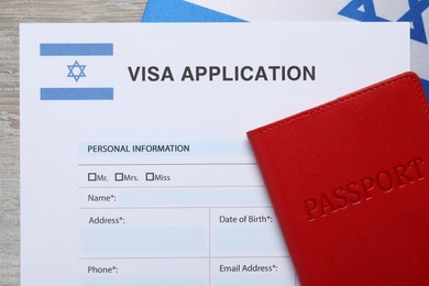 Immigration to Israel. Visa application form, passport and flag on light wooden table, top view