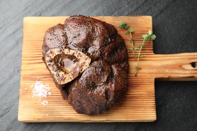 Piece of delicious grilled beef meat, thyme and salt on black table, top view