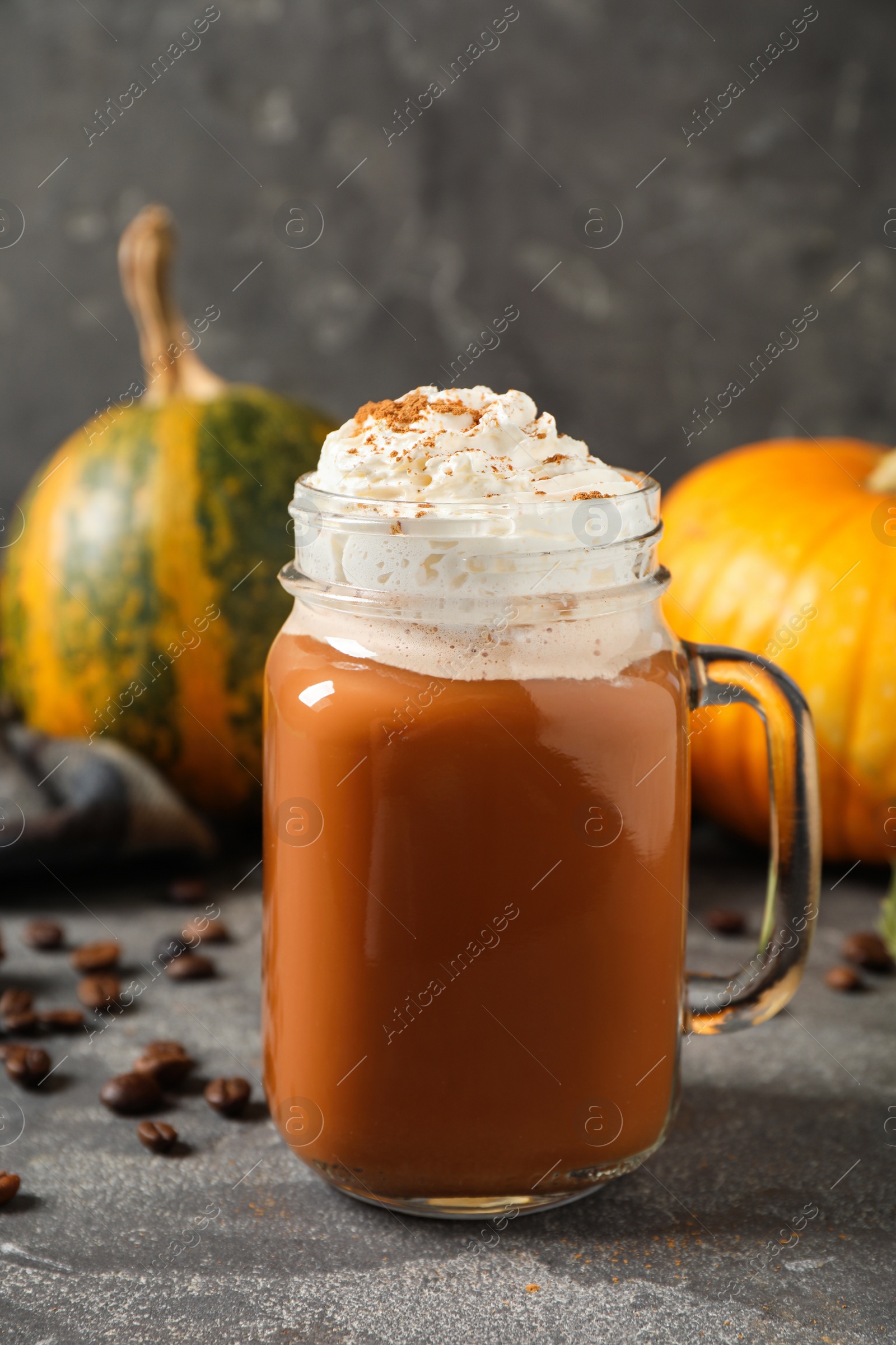 Photo of Mason jar with tasty pumpkin spice latte on grey table