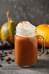 Mason jar with tasty pumpkin spice latte on grey table