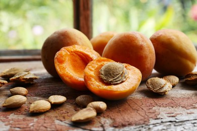 Photo of Delicious ripe apricots with stones on wooden table near window, closeup
