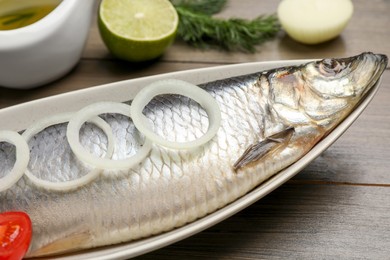 Delicious salted herring and ingredients on wooden table, closeup