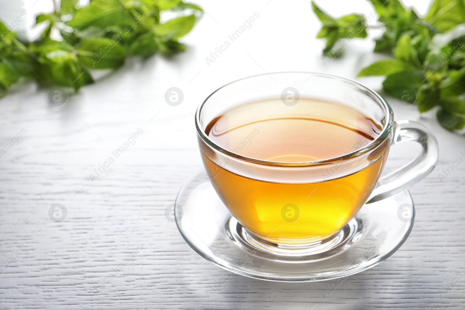 Photo of Cup with hot aromatic mint tea on table