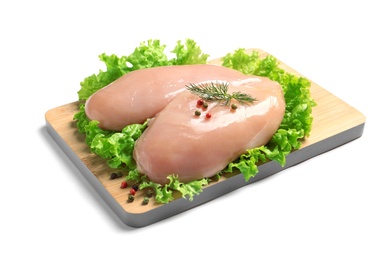 Wooden board with raw chicken breasts and lettuce on white background