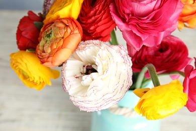 Photo of Bouquet of beautiful bright ranunculus flowers in vase on light table, closeup