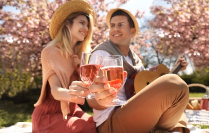 Photo of Happy couple having picnic in park, focus on glasses of wine