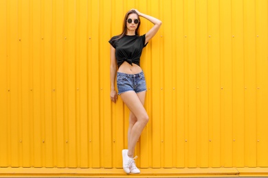 Young woman wearing black t-shirt near color wall on street