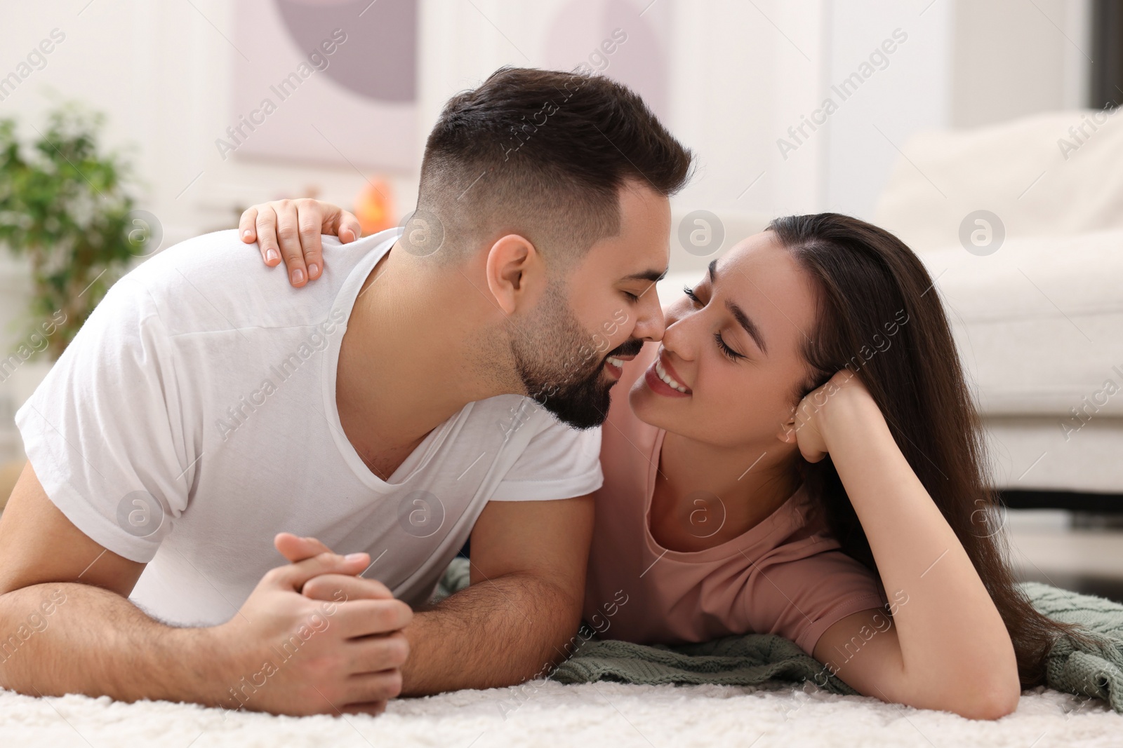 Photo of Affectionate young couple spending time together on soft carpet at home