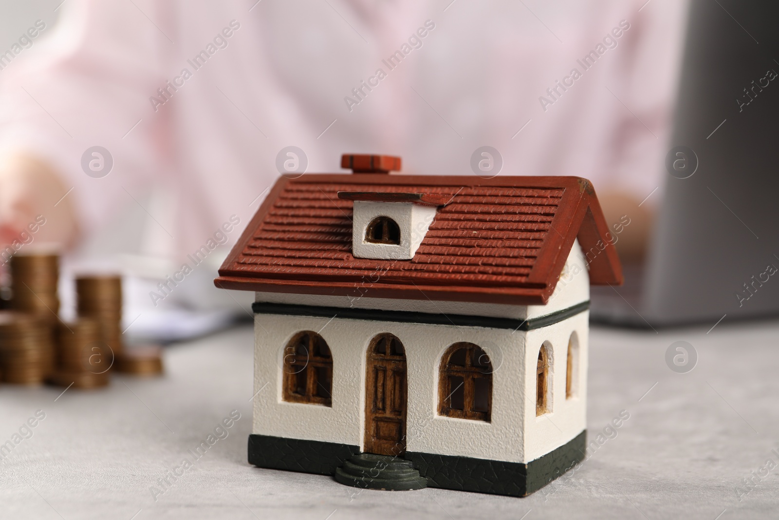 Photo of Woman planning budget at grey table, focus on house model