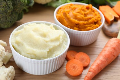 Photo of Bowls with tasty puree and ingredients on wooden table, closeup