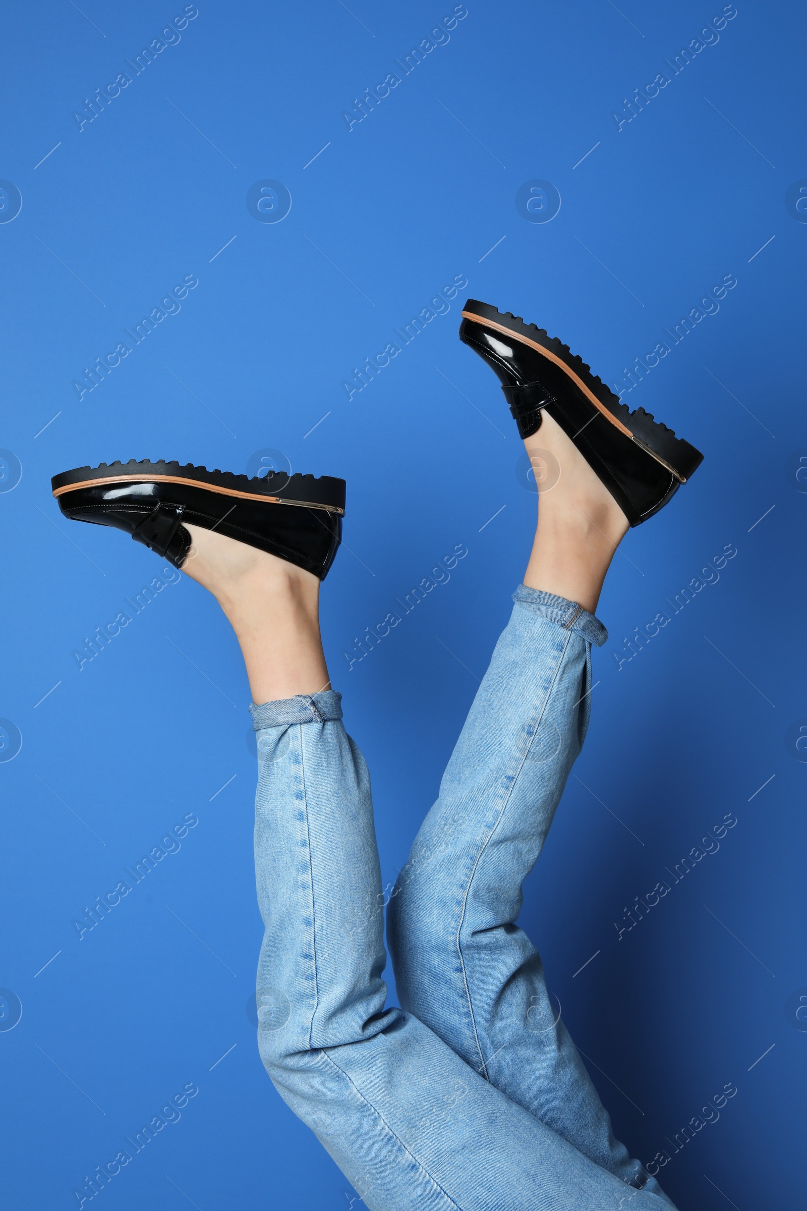 Photo of Woman wearing stylish shoes on blue background, closeup