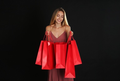 Happy young woman with shopping bags on dark background. Black Friday Sale