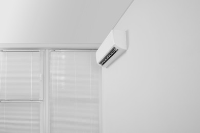 Photo of Modern air conditioner on white wall indoors, low angle view. Space for text