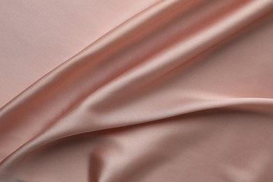 Crumpled pink silk fabric as background, top view