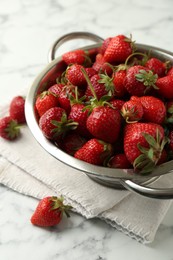 Photo of Metal colander with fresh strawberries on white marble table