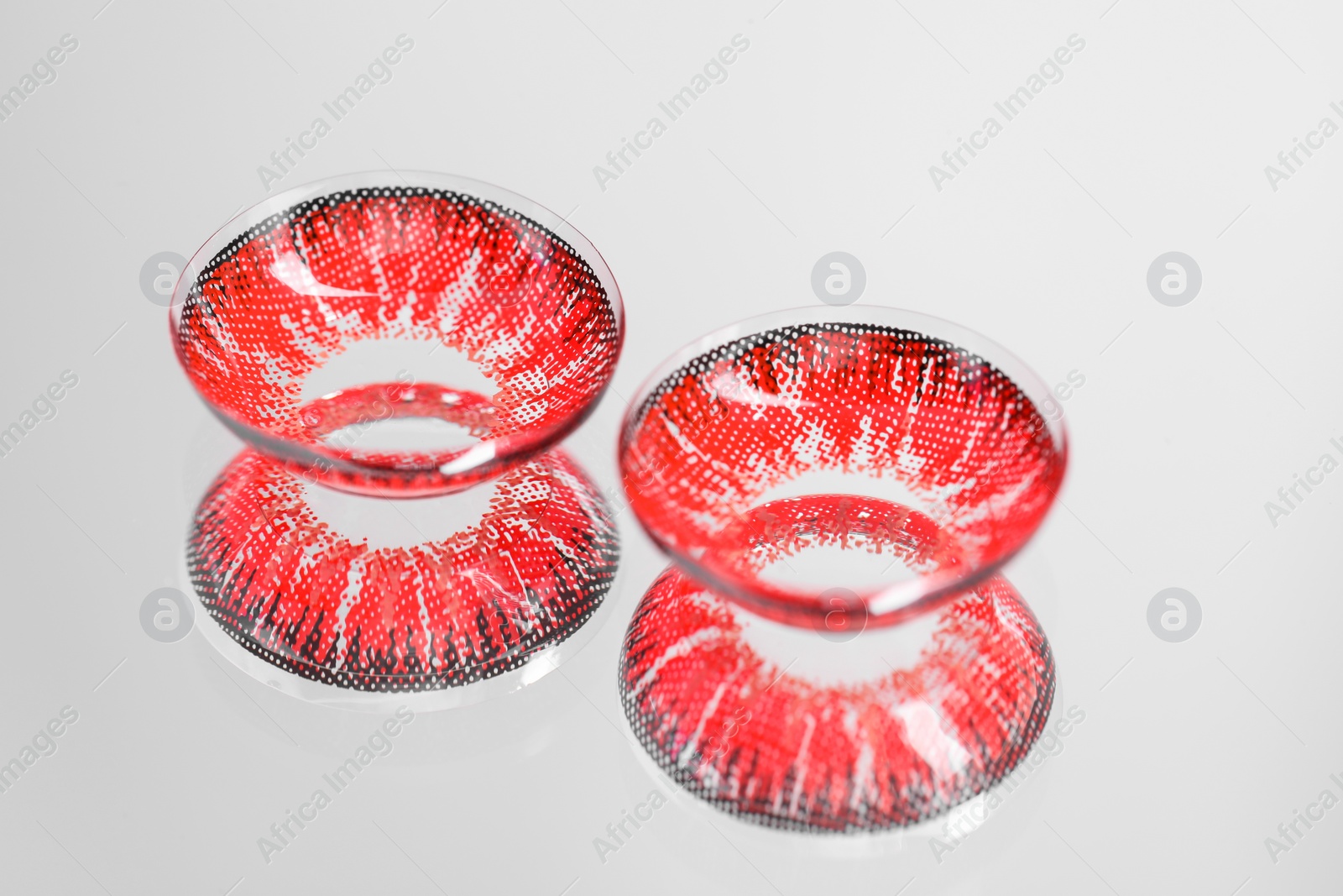 Photo of Two red contact lenses on mirror surface