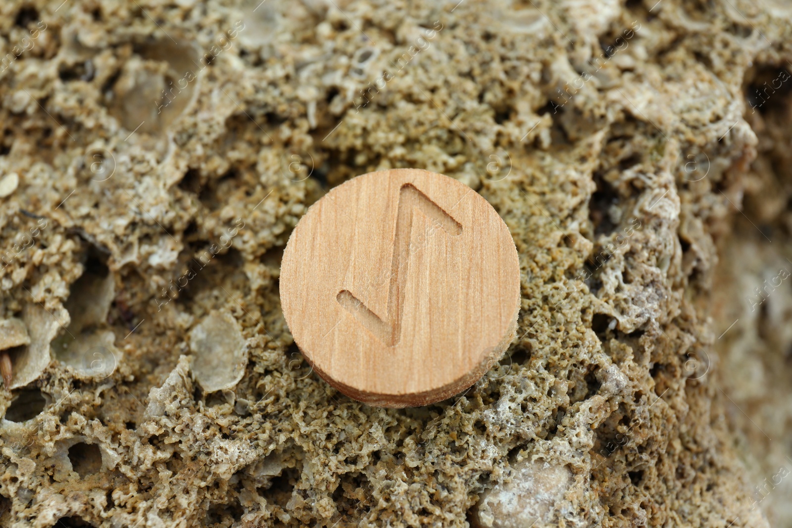 Photo of Wooden rune Eihwaz on stone outdoors, closeup