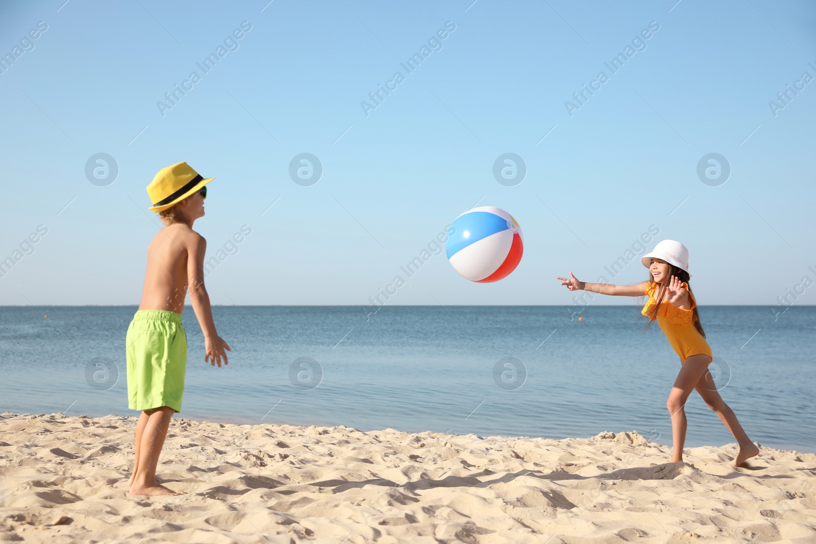 Photo of Cute little children playing with inflatable ball on sandy beach