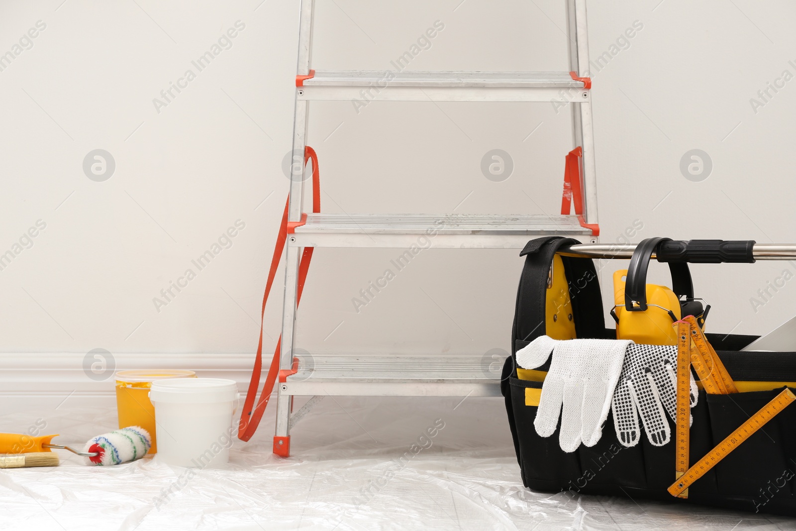 Photo of Stepladder and different tools near wall in room. Interior renovation