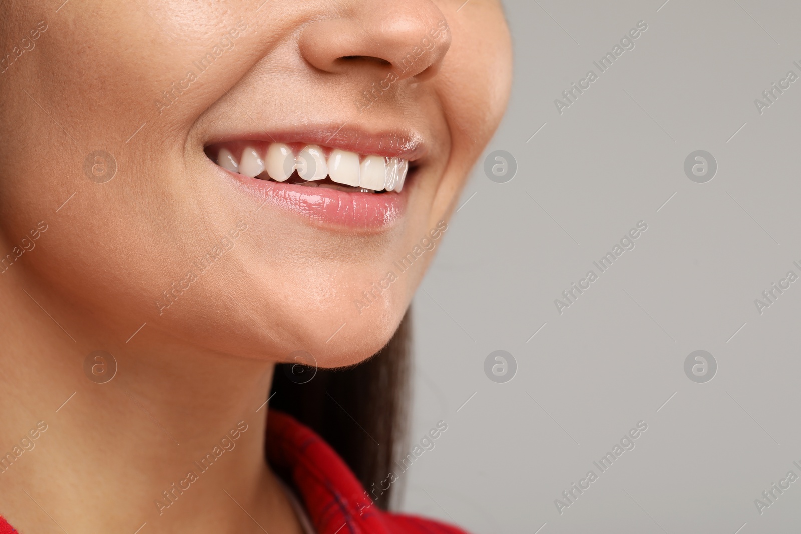 Photo of Young woman with clean teeth smiling on light grey background, closeup. Space for text