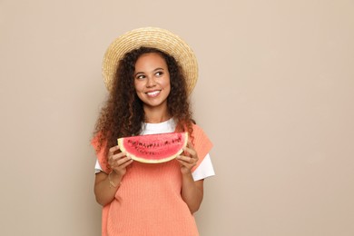 Photo of Beautiful young African American woman with slice of watermelon on beige background. Space for text