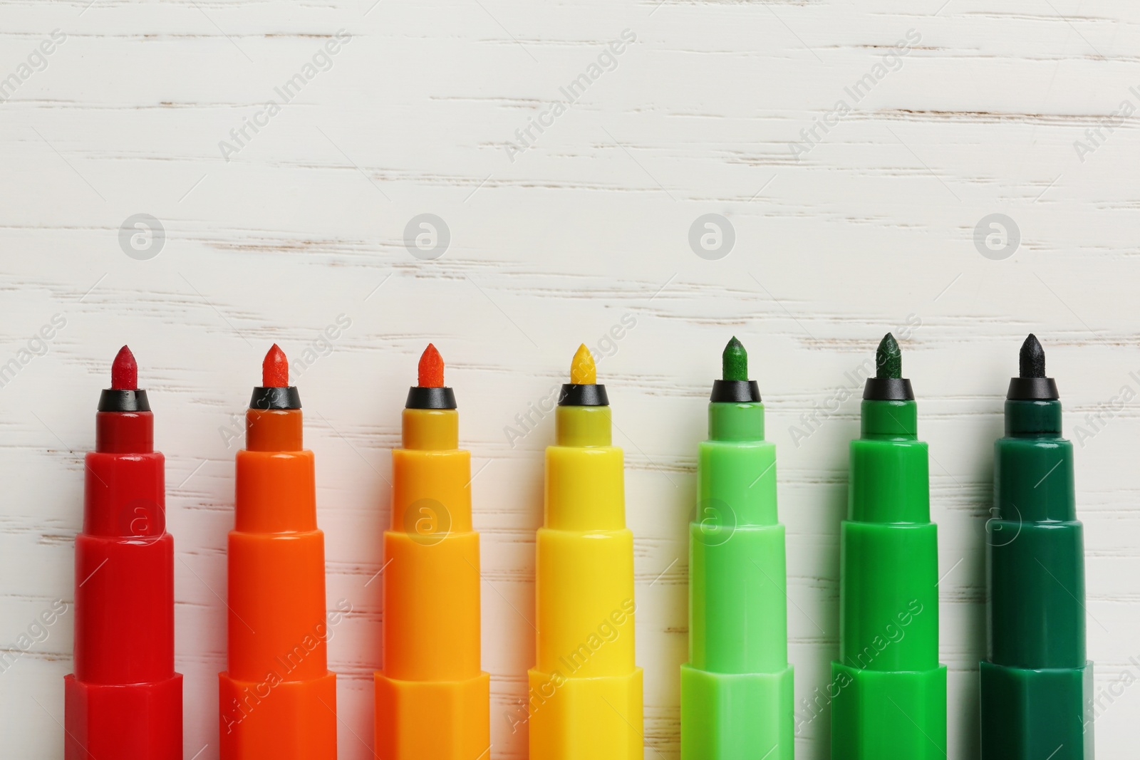 Photo of Colorful markers and space for text on white wooden background, flat lay. Energy efficiency concept