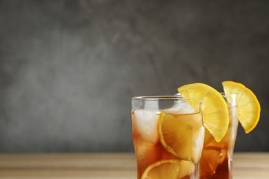 Photo of Glasses of tasty ice tea with lemon on grey background, space for text