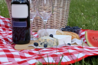 Picnic blanket with delicious food and wine outdoors on summer day, closeup