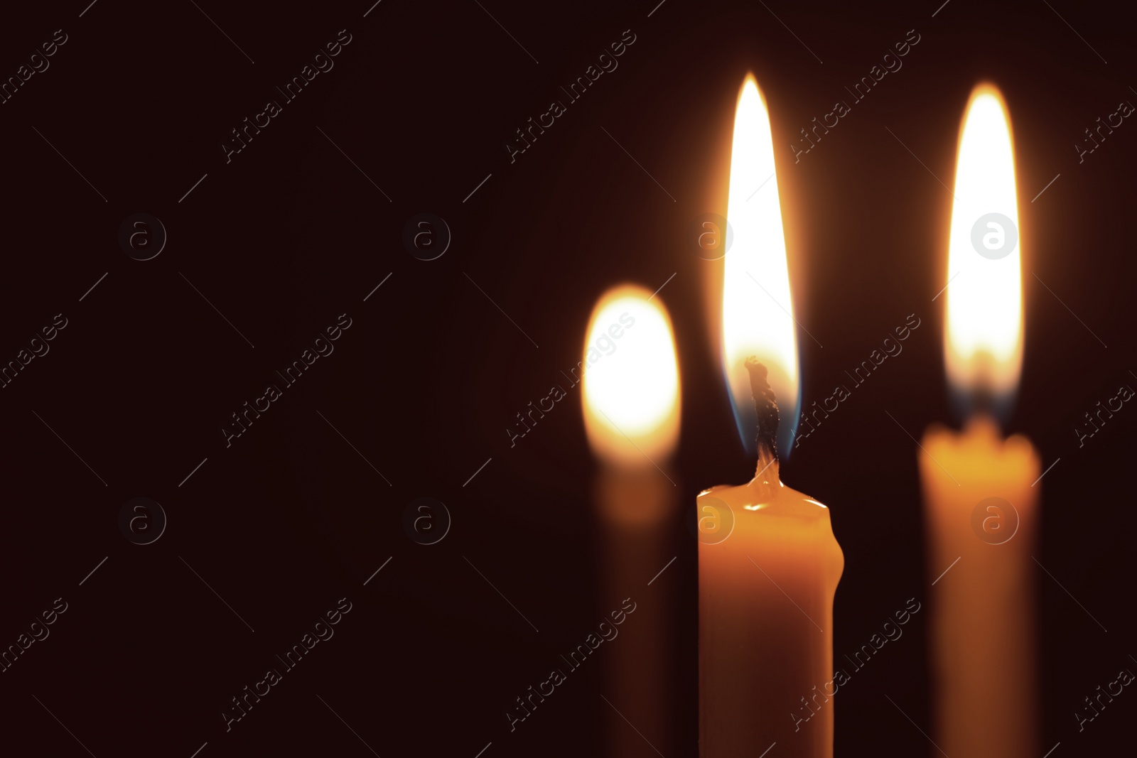 Photo of Burning candles on dark background, space for text. Symbol of sorrow