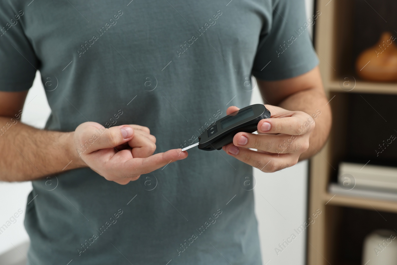 Photo of Diabetes test. Man checking blood sugar level with glucometer at home, closeup