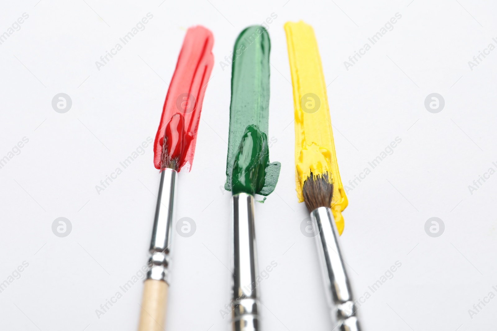 Photo of Brushes with different paints and strokes on white background, flat lay