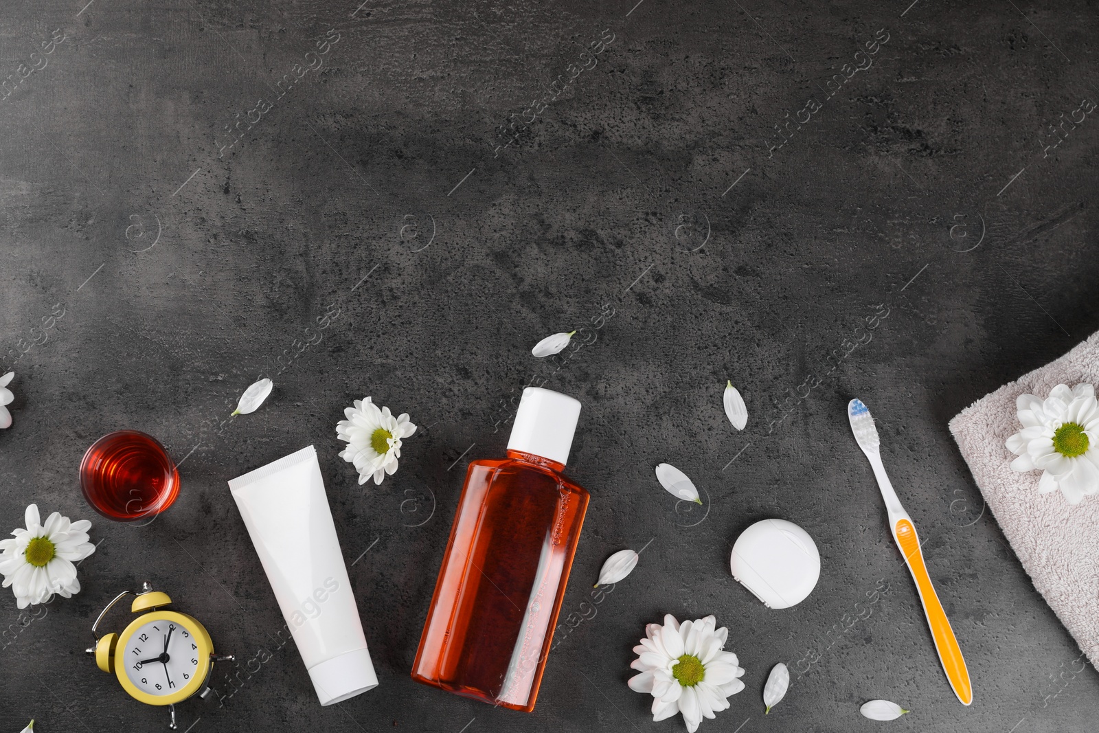 Photo of Fresh mouthwash and other oral care products on dark textured table, flat lay. Space for text
