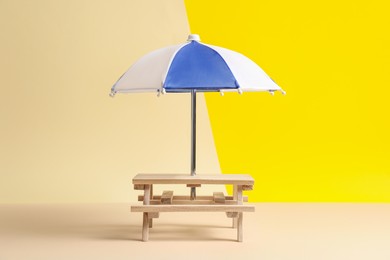 Photo of Small wooden holder with toy umbrella on color background