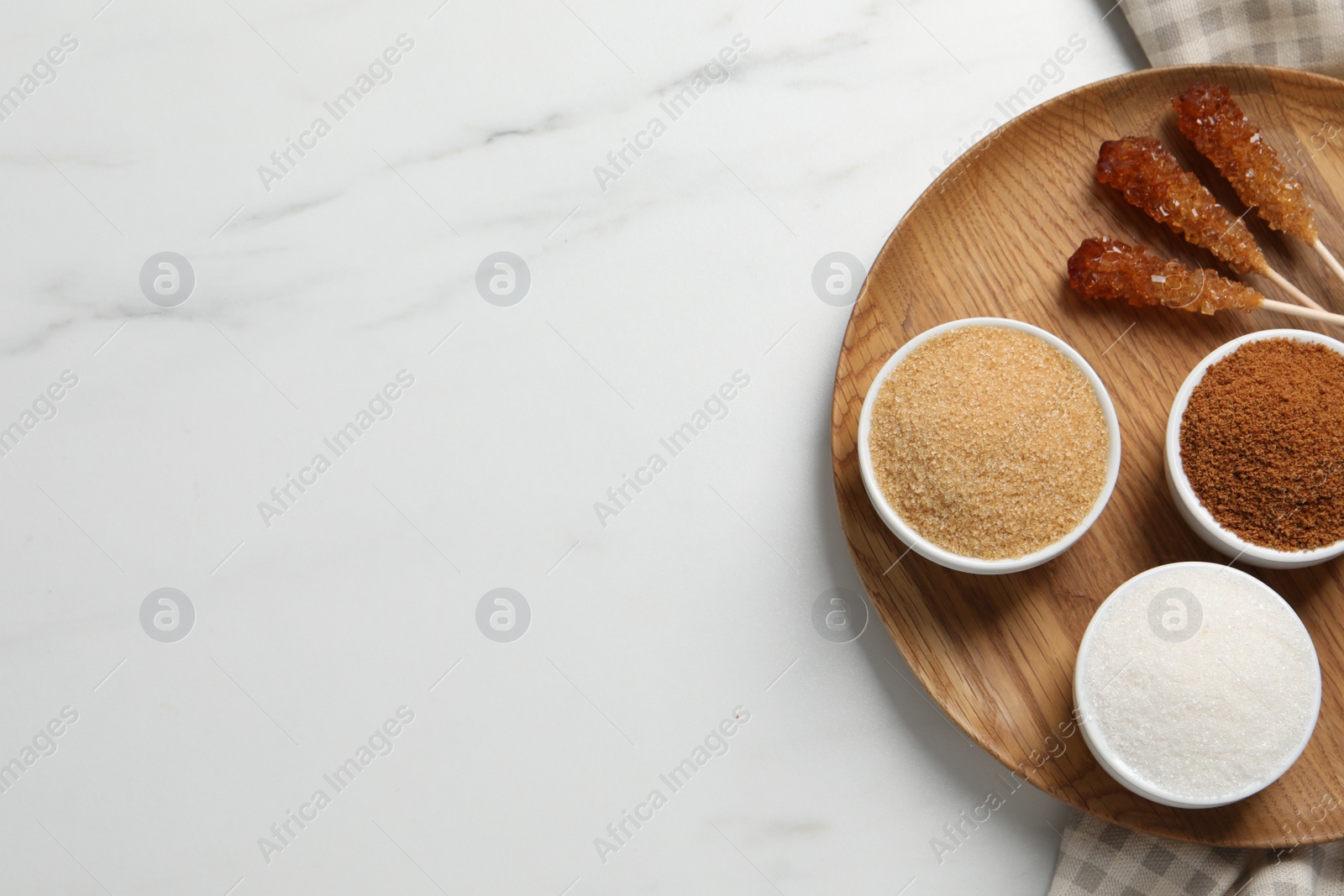 Photo of Board with different types of sugar on white marble table, top view. Space for text