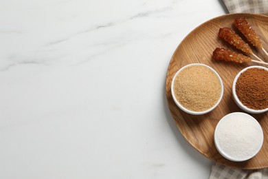 Board with different types of sugar on white marble table, top view. Space for text