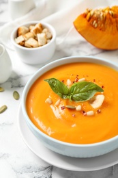 Photo of Delicious pumpkin soup in bowl on marble table, closeup