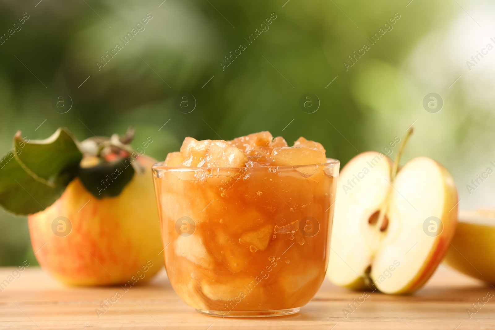 Photo of Delicious apple jam and fresh fruits on wooden table