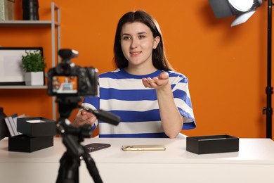 Photo of Smiling technology blogger explaining something while recording video at home