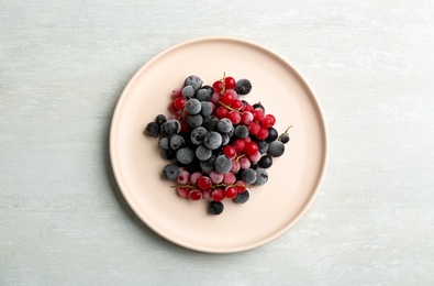 Tasty frozen red and black currants on white table, top view