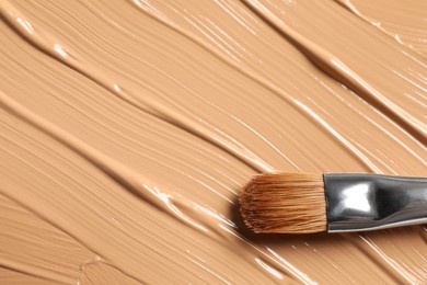 Photo of Skin foundation and makeup brush as background, closeup