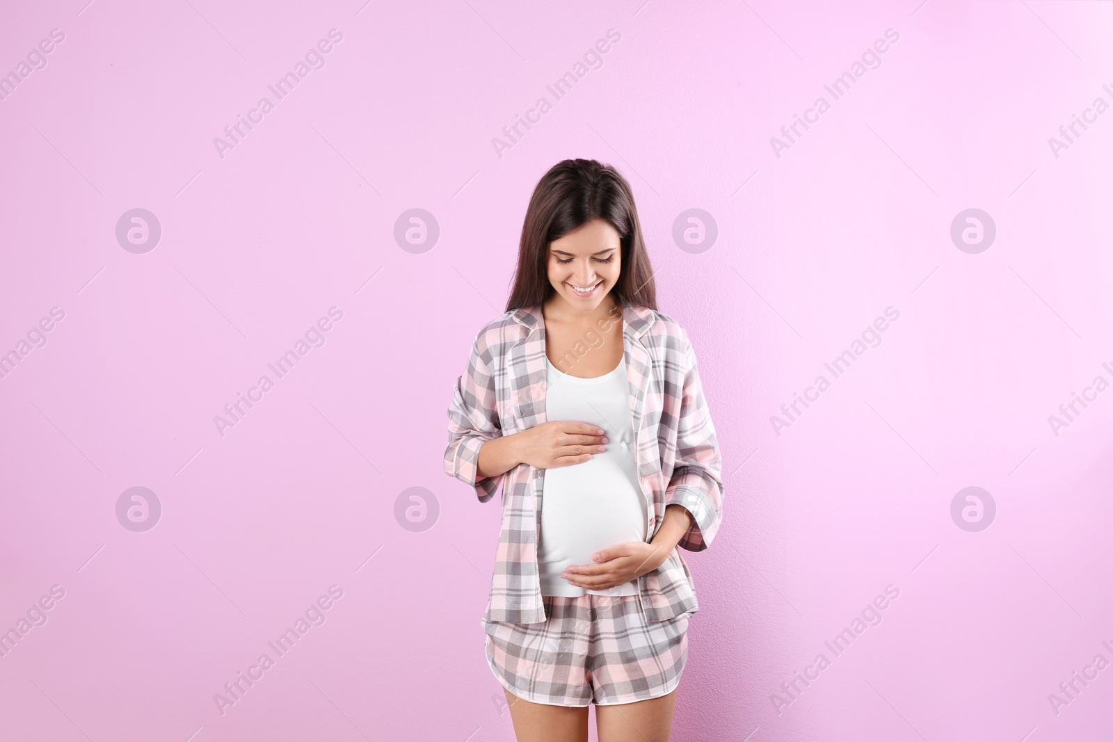 Photo of Happy pregnant woman posing on color background