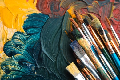 Photo of Different paint brushes on canvas, top view with space for text