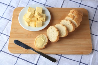 Photo of Cut baguette with fresh butter on checkered tablecloth