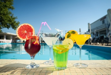 Tasty refreshing cocktails on edge of swimming pool. Party drinks