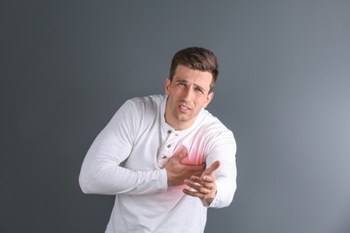 Photo of Young man having heart attack on gray background