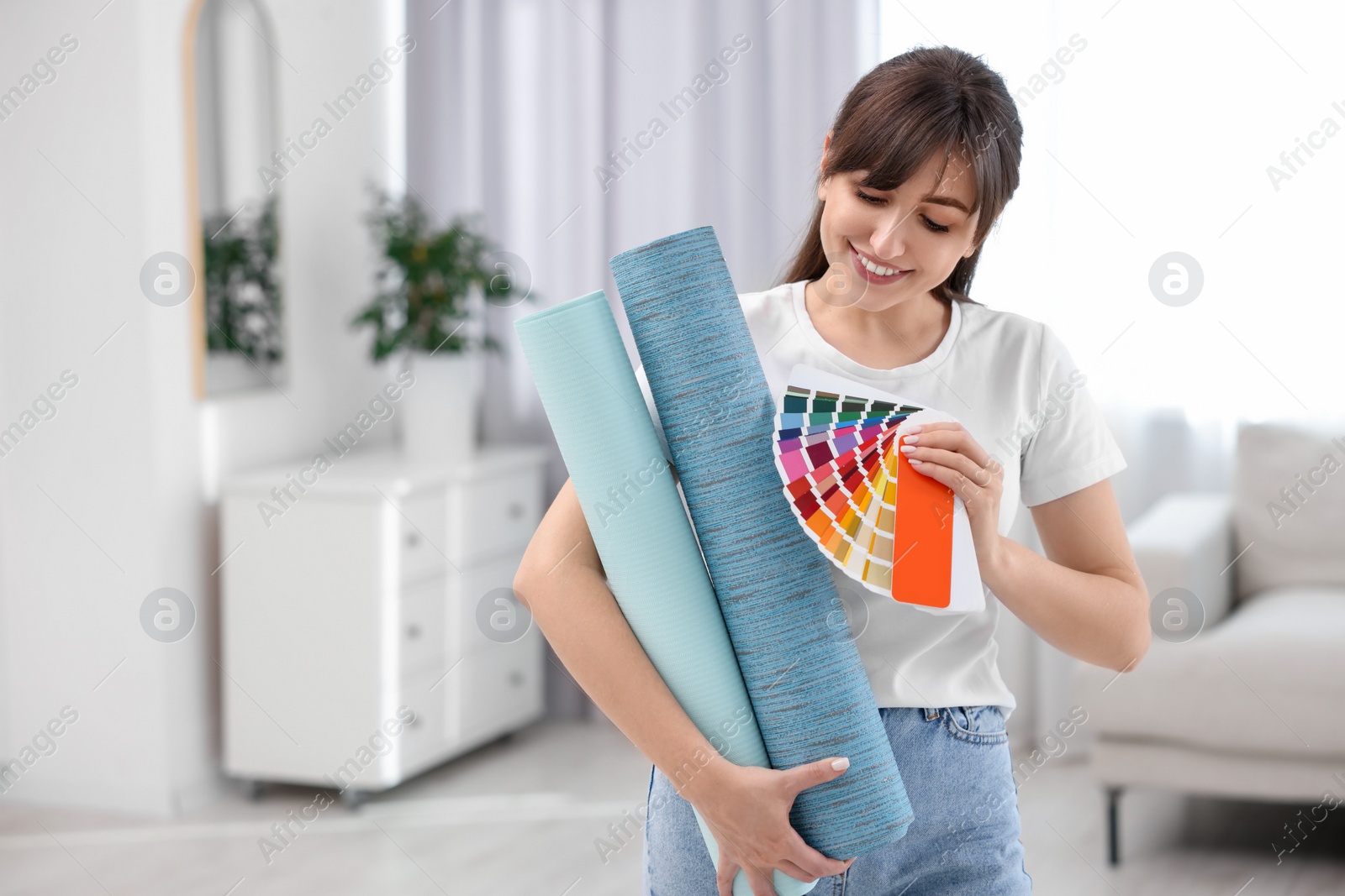 Photo of Woman with wallpaper rolls and color palette in room